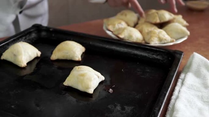 女性双手的特写镜头将烤盘上的热甜百吉饼和面包铺在盘子上，奶奶为家人自制烘烤。