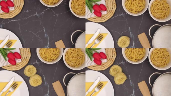 厨房用具，白色碗中的意大利面和红色郁金香出现在黑色大理石背景上-停止运动