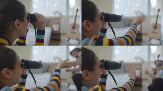 新型冠状病毒肺炎检疫。想象中的假期。顽皮的年轻女子透过双筒望远镜向远处的某人挥手。呆在家里玩得开心。