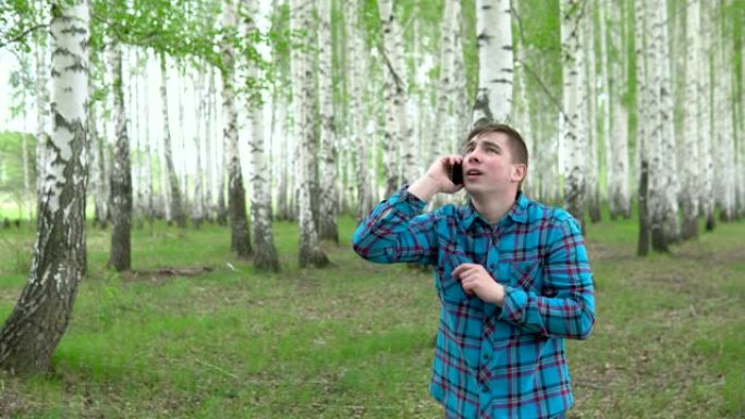 一个年轻人正在白桦林中寻找蜂窝网络。一名男子正在打电话，但连接中断。这个人很紧张。