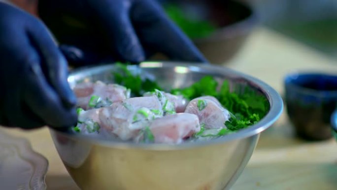 将盐倒在蔬菜上，然后将肉腌制在碗中。用草药烹饪肉的过程。肉块干扰碗中。特写。