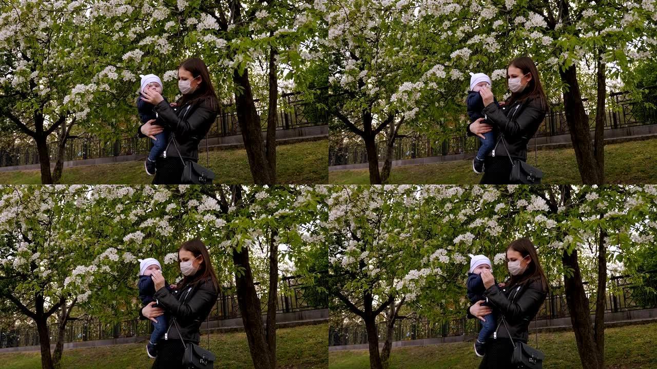 春天，戴着医用口罩的母亲在公园里抱着一个一岁的孩子。