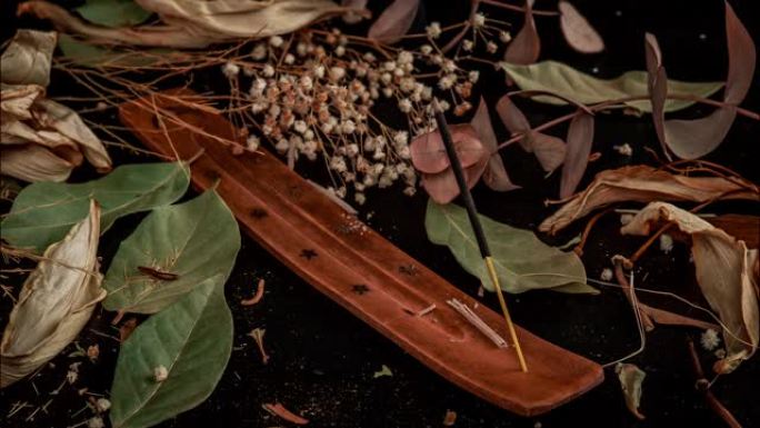 黑色背景上有叶子和花朵的棍棒和香棒