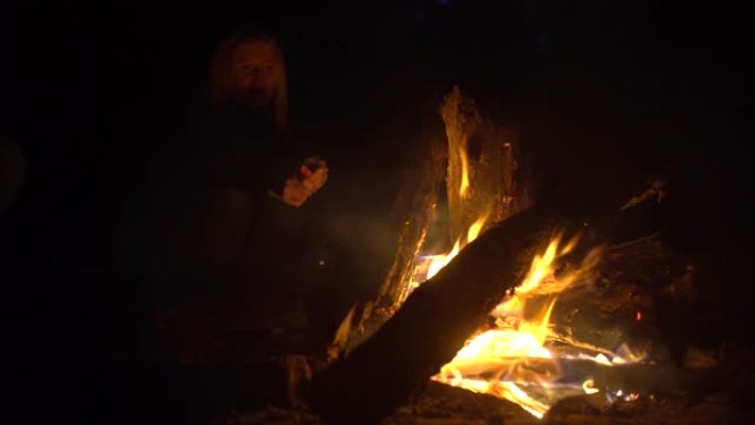 朋友们晚上坐在火炉旁。周围的人篝火，沐浴在火中，放松概念，篝火，放松，希望，人性，自然，游客。