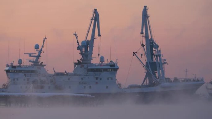 清晨，在雾中日出时，船只在港口