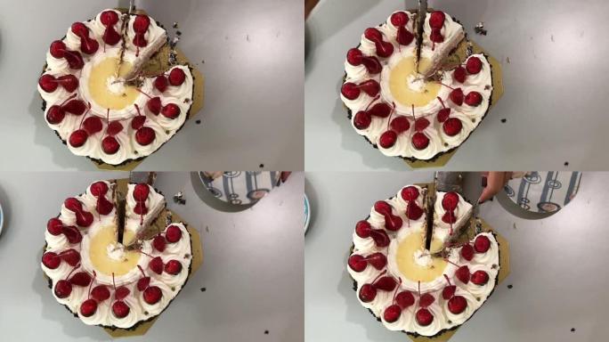 女人的手在办公室的桌子上用草莓白奶油切蛋糕的视频镜头。草莓蛋糕。顶视图。4k视频片段。