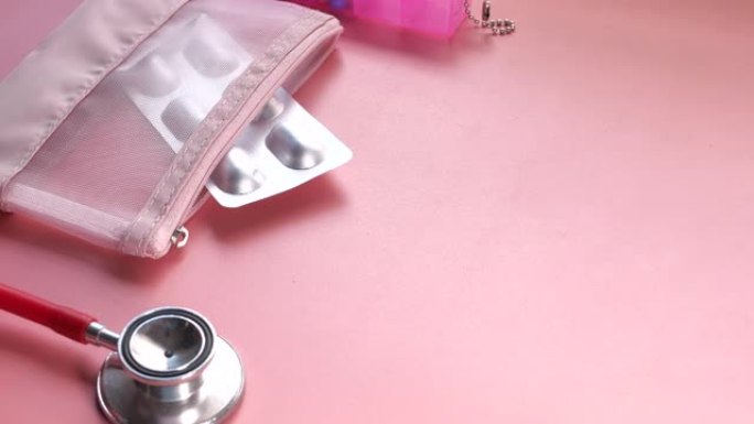 粉色背景上的泡罩包装、听诊器和药盒的俯视图