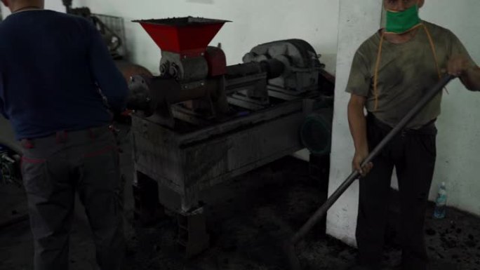 两名男子在工厂的水烟生产线上从事煤炭工作