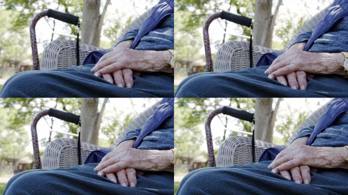 特写镜头拍摄了一名90多岁的老年高加索妇女夏天在户外的手，背景是拐杖
