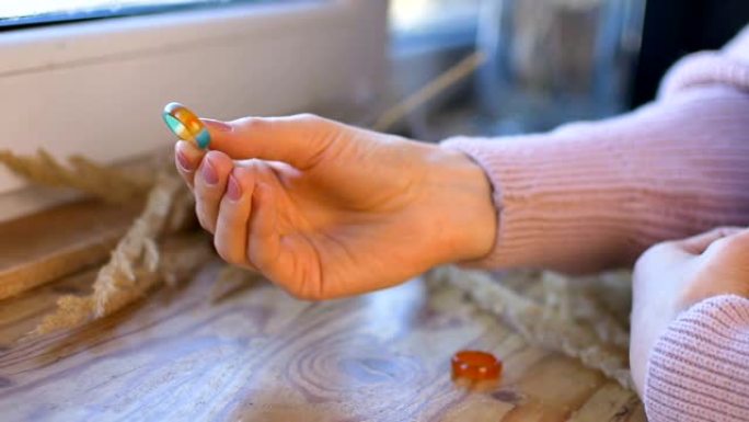 具有天然修指甲的女性手在木制窗台上显示出由玛瑙和蛋白石宝石制成的橙色和绿色宝石戒指，上面有小穗