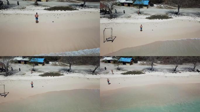 一对年轻夫妇站在印度尼西亚龙目岛粉红海滩海滨的沙滩上玩无人机。波浪轻轻地冲刷着海岸。他正在仔细观察无