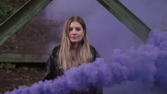 一个年轻的女模特挥舞着烟雾弹，紫色的烟雾将她吞没