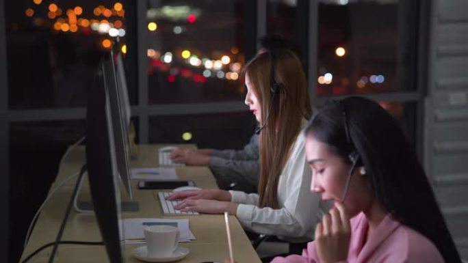 通过在现代办公室中使用计算机和耳机，三个呼叫中心工作到深夜，以帮助全球范围内的业务和IT支持与幸福的