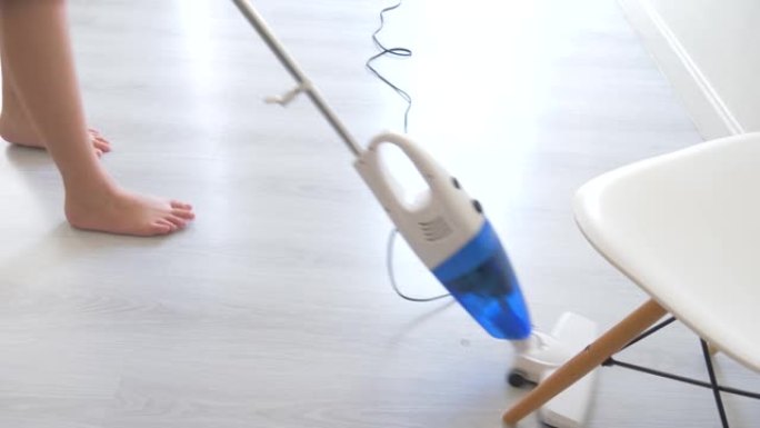亚洲青春期男孩在家使用电动清洁吸尘器。