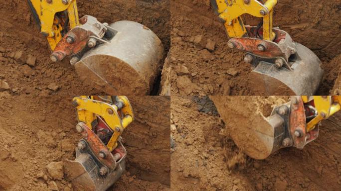 强大的挖掘机的铲斗从坑中清除土壤，铺设管道
