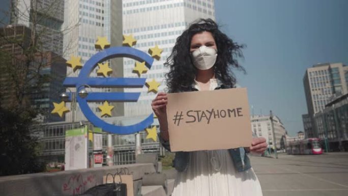 德国法兰克福，2020年4月8日一名年轻妇女在欧洲新型冠状病毒肺炎病毒举着 # stayhome标志