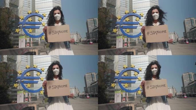 德国法兰克福，2020年4月8日一名年轻妇女在欧洲新型冠状病毒肺炎病毒举着 # stayhome标志