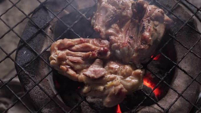 鸡大腿在传统的炉子上烤制。充满了炽热的火焰和烟雾。具有户外感觉的泰国街头美食。