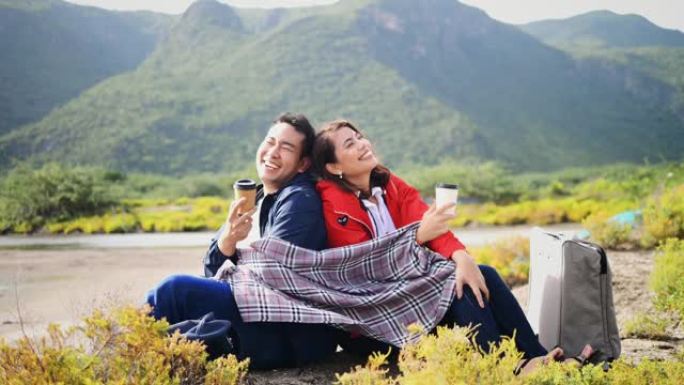 快乐的亚洲夫妇露营和喝咖啡与自然背景，生活方式的概念。