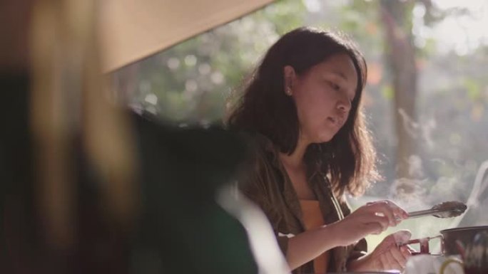 野营时用平底锅煮早餐的年轻女子。