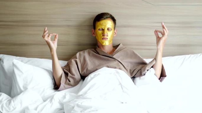 穿着金色面具的男人在酒店的床上冥想