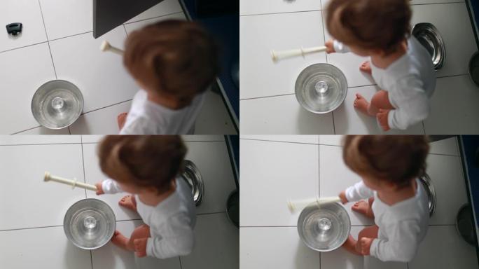 婴儿在厨房地板上玩平底锅和锅。一岁幼儿婴儿撞击金属器具