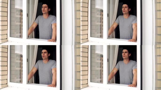 一个悲伤的家伙站在敞开的窗户附近，试图冷静下来。问题和抑郁。