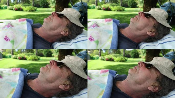 男人在外面睡着，脸上盖着帽子