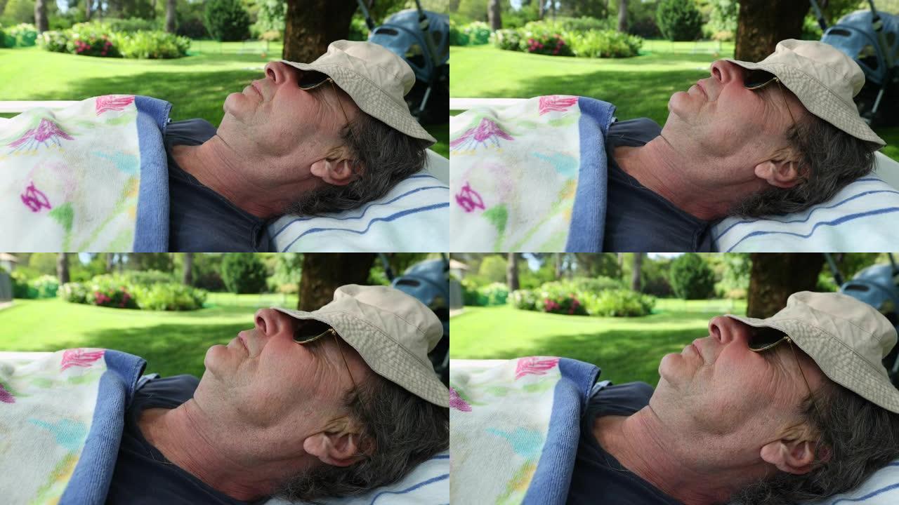 男人在外面睡着，脸上盖着帽子