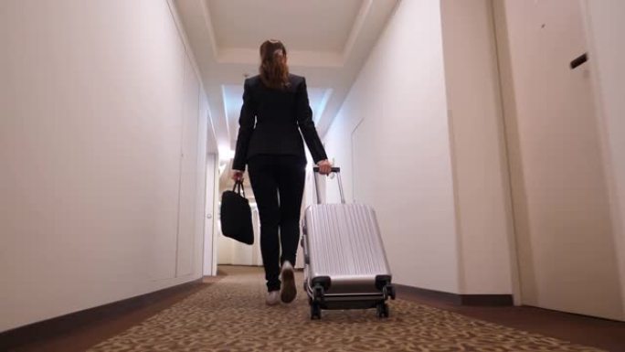女人拿着手推车走在酒店走廊，转到电梯大厅