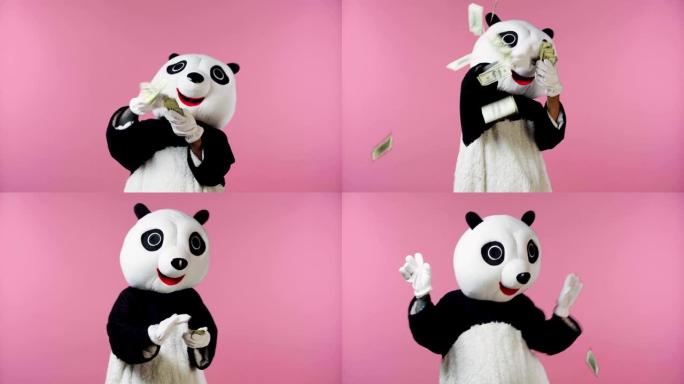 穿着熊猫熊服装的人在空气中扔钱隔离在粉红色上