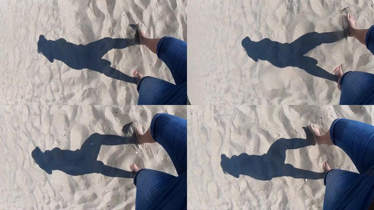 在岸上的沙滩上散步的女孩的黑影