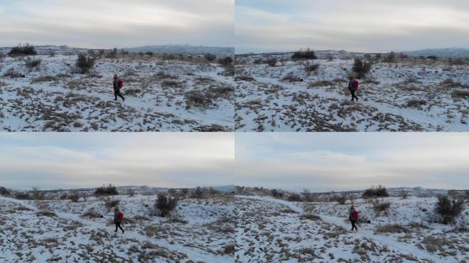 女人独自在卡帕多西亚山谷徒步旅行的空中冬季景观