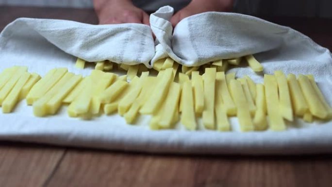 用毛巾沥干一堆生的楔形土豆。从土豆中榨水。