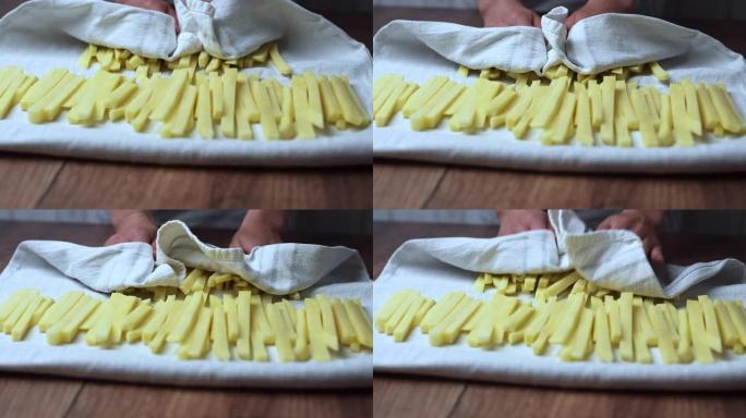 用毛巾沥干一堆生的楔形土豆。从土豆中榨水。