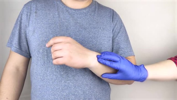 一个男人的手腕疼。创伤学家检查一只手。手腕疼痛是隧道综合征或扭伤，肌腱退化，关节炎的征兆