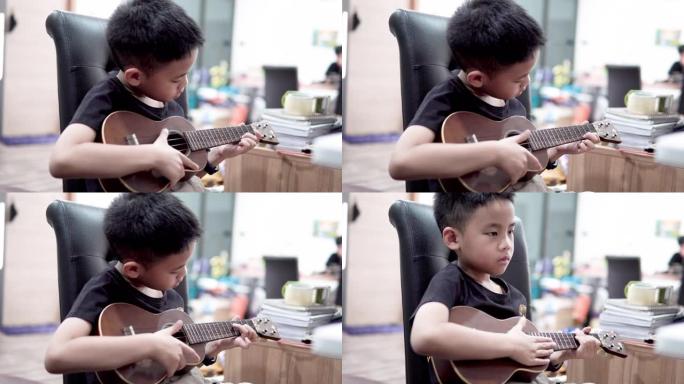 可爱的男孩在家里学习演奏夏威夷四弦琴。