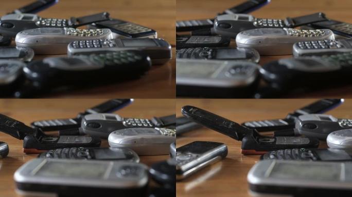 旧的破损的刮擦和尘土飞扬的手机堆在桌子上。