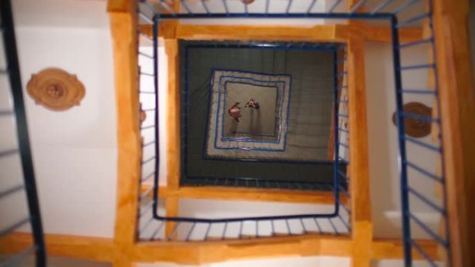 镜子天花板上两个人的倒影。围绕着方形的螺旋楼梯。