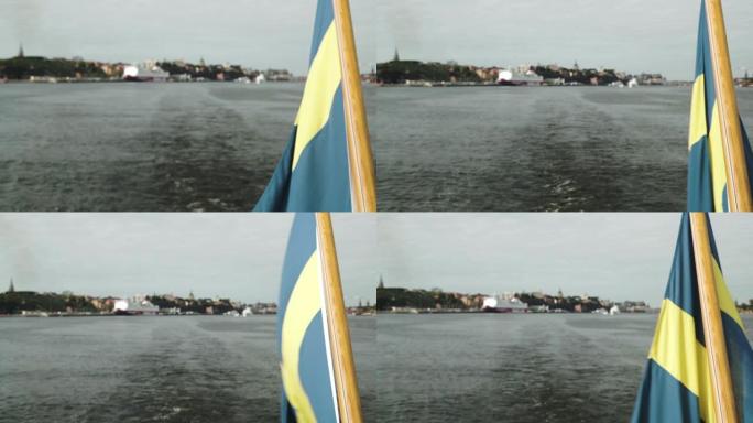 瑞典国旗在风中挥舞在斯德哥尔摩市中心港口航行的船尾尾饲料旗杆上的特写