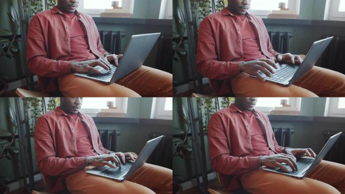 非裔美国人在办公室休息区的膝盖上使用笔记本电脑