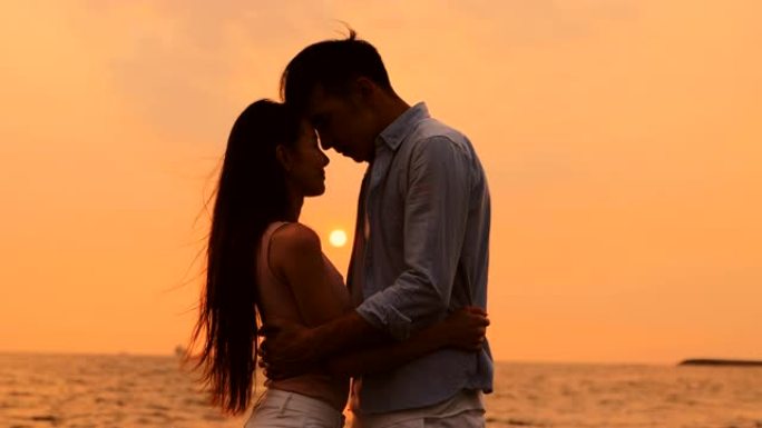 浪漫的年轻夫妇在日落时在海滩上拥抱