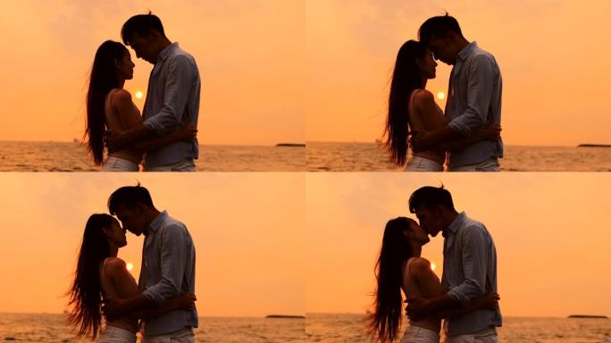 浪漫的年轻夫妇在日落时在海滩上拥抱