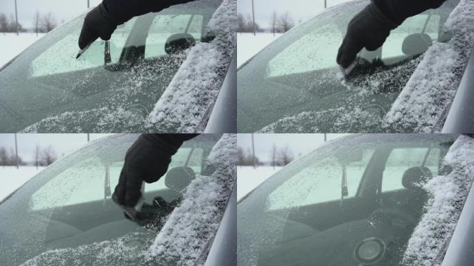 在冬天，用刮刀将汽车挡风玻璃或挡风玻璃上的雪和冰清理干净。手臂上有刮板或刮毛器。又冷又坏的天气。白天