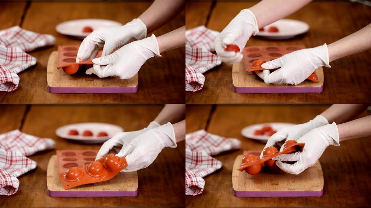 女性双手从柔性硅胶模具中取出草莓果冻，特写镜头。