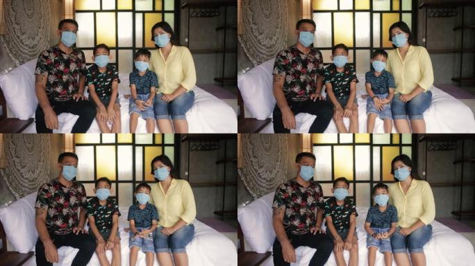 家庭检疫期间戴着医用口罩的亚洲家庭。印尼或马拉西亚的父母和孩子在冠状病毒新型冠状病毒肺炎爆发期间在家