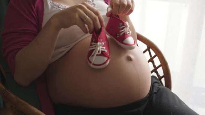 女手玩剧走路走路宝宝小鞋在怀孕的肚子上