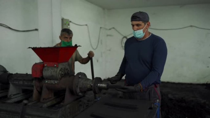 两名男子在工厂的水烟生产线上从事煤炭工作