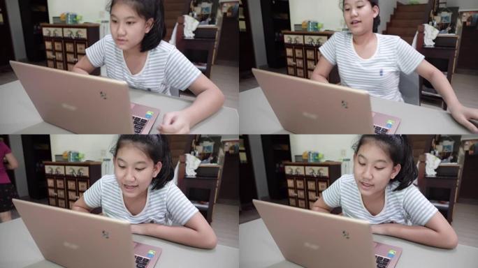 年轻的亚洲妇女使用笔记本电脑学习通话视频会议与老师在家里的客厅。