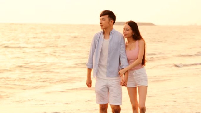快乐的亚洲年轻夫妇在日落时在沙滩上散步